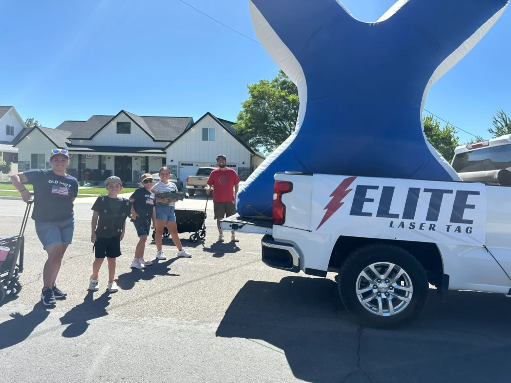 Group by Elite Laser Tag truck with inflatable X on sunny day.
